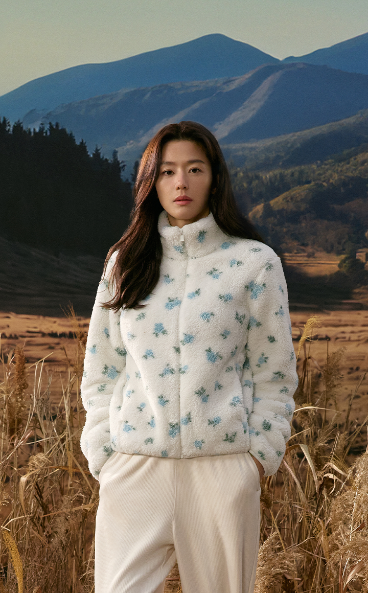 가을 산과 갈대밭을 배경으로 플라워 패턴 플러피 플리스 집업을 입은 여성 모델